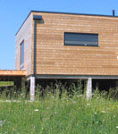 Vue extérieure de la construction d'une maison écologique bois réalisée avec un mur pré-fabriqué (menuiseries intégrées)
